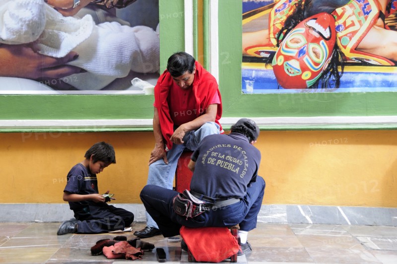 Mexico, Puebla, Shoeshine stand in front of posters. Photo : Nick Bonetti