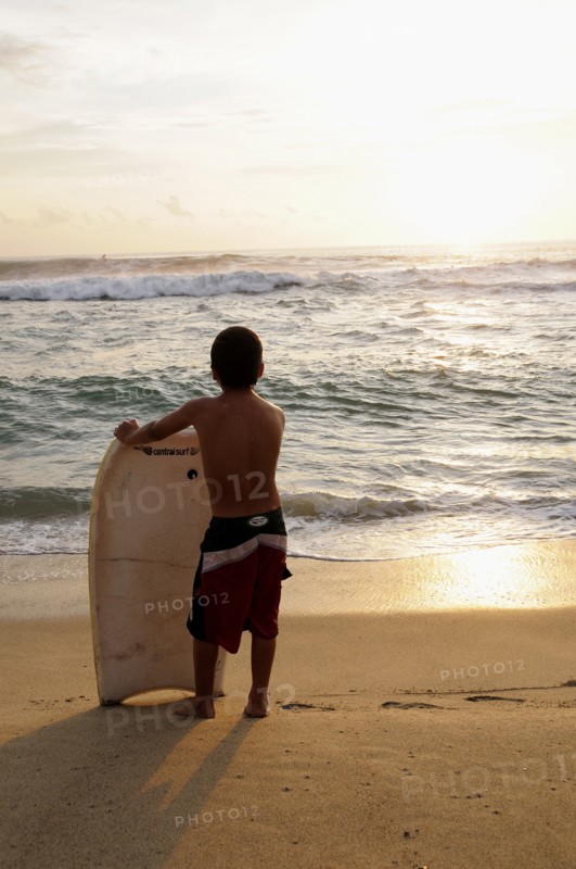 Mexico, Oaxaca, Puerto Escondido, Playa Zicatela Young body boarder standing on beach looking out to sea.. Photo : Nick Bonetti