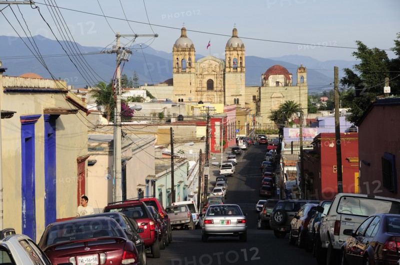 Mexico, Oaxaca, View along street lined by parked vehicles towards church of Santo Domingo. Photo : Nick Bonetti