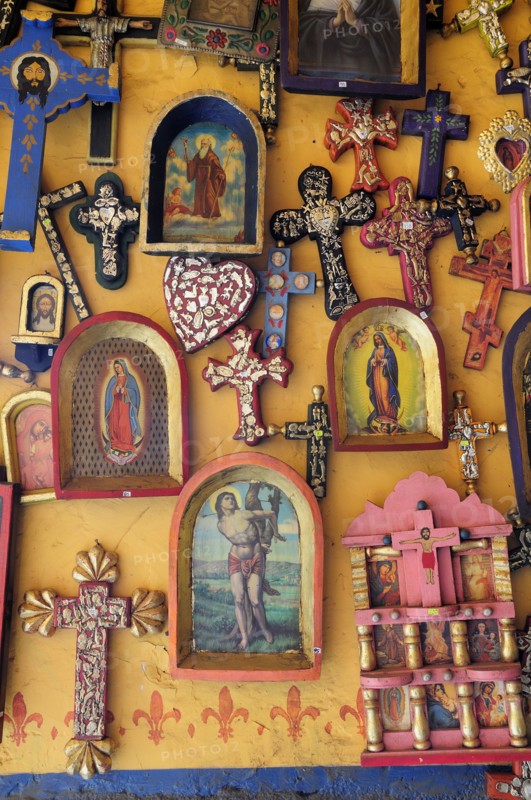 Mexico, Michoacan, Patzcuaro, Religious kitsch art displayed on yellow painted wall. Photo : Nick Bonetti