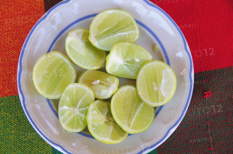 Mexico, Oaxaca, Huatulco, Blue and white bowl with cut halves of limes on red and green woven cloth. Photo : Nick Bonetti