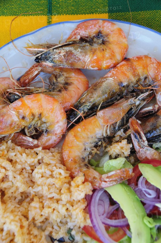 Mexico, Oaxaca, Huatulco, Gambas or prawns served on blue and white plate with sliced onion avocado tomato and couscous salad. Photo : Nick Bonetti