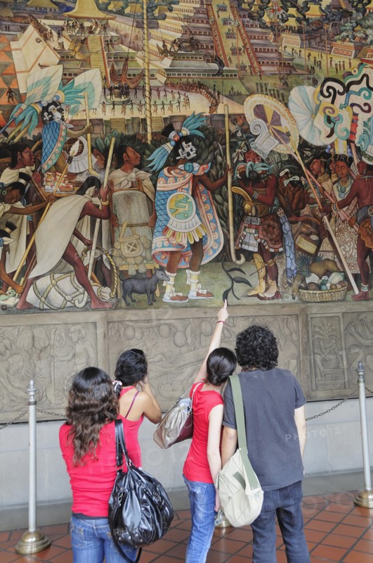 Mexico, Federal District, Mexico City, Group of visitors looking at mural by Diego Rivera depicting life before the Conquest in the Palacio Nacional. Photo : Nick Bonetti