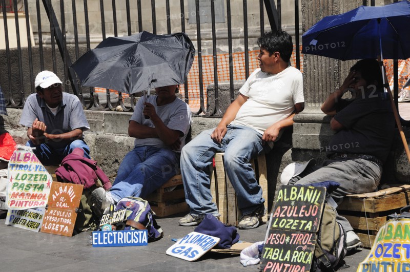 Mexico, Federal District, Mexico City, Workers plying trade outside the Cathedral in the Zocalo using umbrellas for shade. Photo : Nick Bonetti