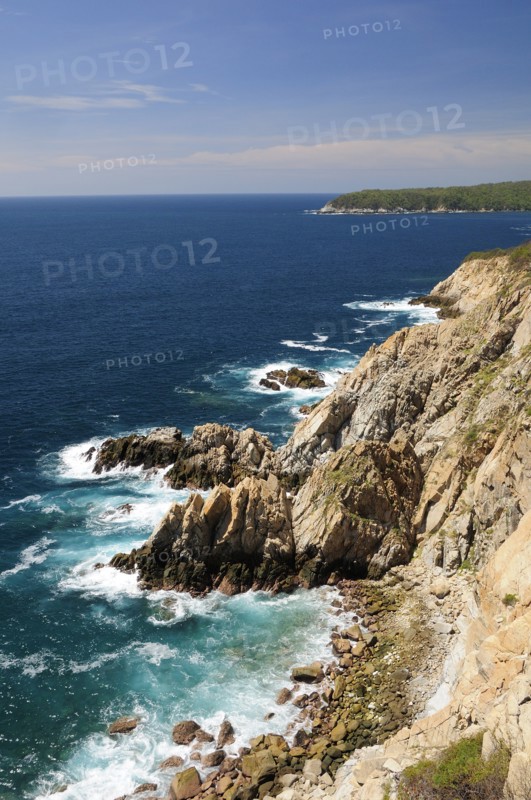 Mexico, Oaxaca, Huatulco, Rocky cliff edge with waves breaking on rocks below and Bahia Maguey. Photo : Nick Bonetti