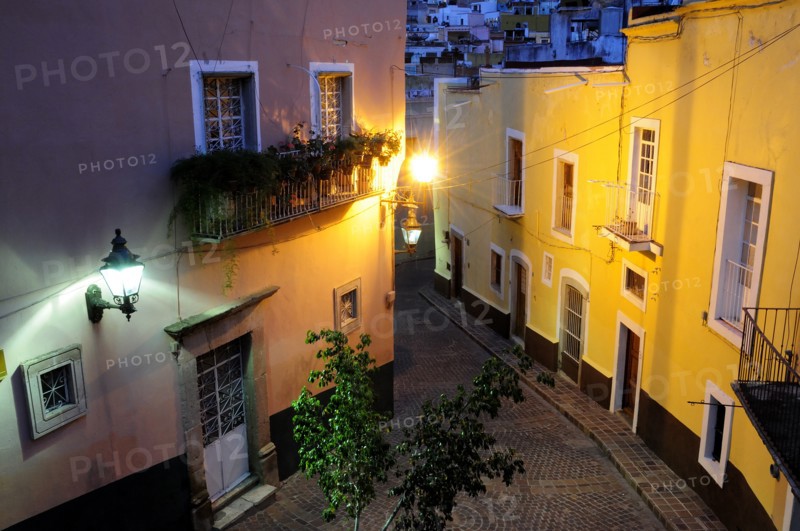 Mexico, Bajio, Guanajuato, Elevated view over street corner at night with painted building facades balconies and illuminated street lights. Photo : Nick Bonetti