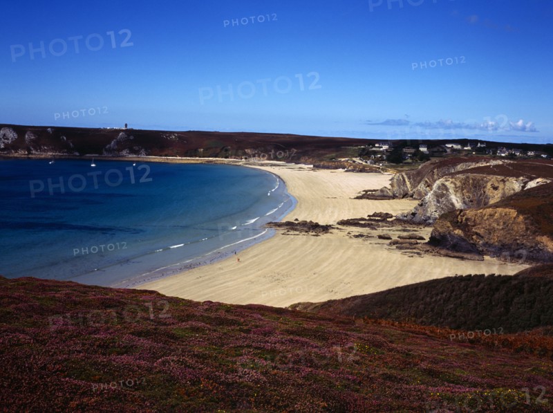 France, Bretagne, Crozon Peninsula, Veryach Beach. Stretch of sandy beach with three figures. Heather clad cliffs in foreground houses and other buildings in far distance. Photo : Bryan Pickering