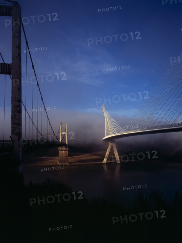 France, Bretagne, Finistere, Ile de Crozon. View of both old and new Pont de Terenez suspension bridges from north bank of the River Aulne in early morning fog. Photo : Bryan Pickering