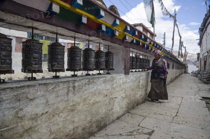 Nepal, Upper Mustang, Kagbeni, Woman prays using prayer wheels. Photo : Sergey Orlov