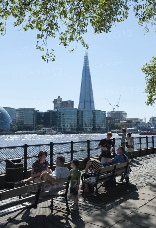 England, London, People relaxing on the North Bank of the river Thames with the Shard visible behind. Photo : Paul Tomlins