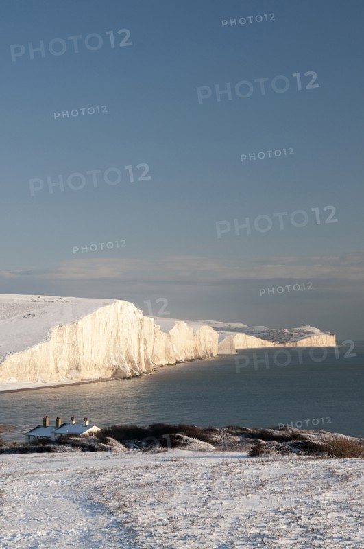 England, East Sussex, Seven Sisters, Snow covered coastline from Birling gap showing the Coastguard cottages in the foreground and Belle Tout lighthouse in the distance.. Photo : Bob Battersby