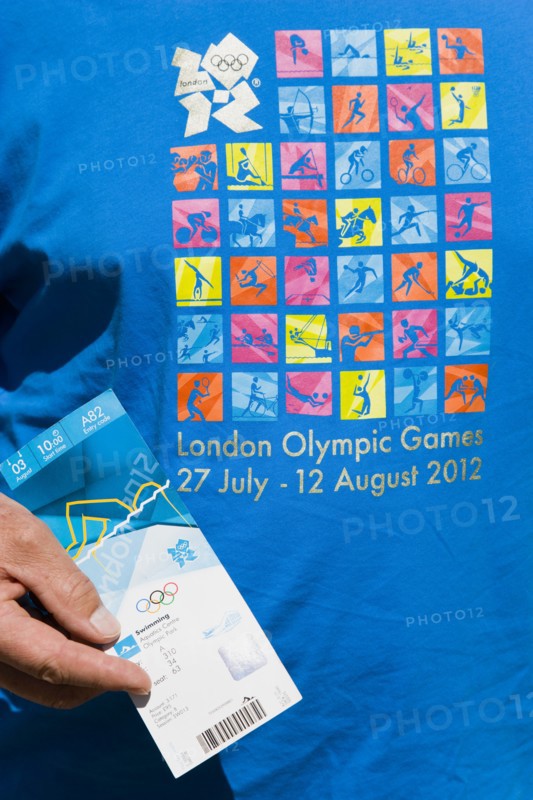 England, London, An Olympic spectator wearing an official T-shirt holding their official ticket for a Swimming session in the Aquatic Centre in the Olympic Park. Photo : Paul Seheult