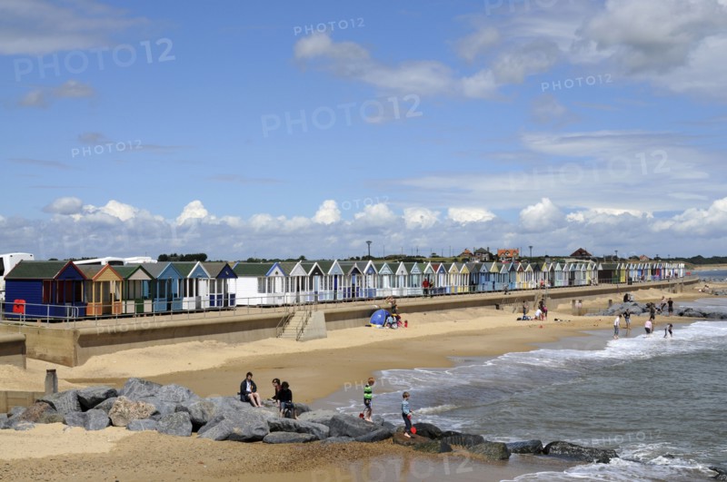 England, Suffolk, Southwold, Beach Huts near the pier with Sea Defences and Holidaymakers. Photo : Bob Battersby