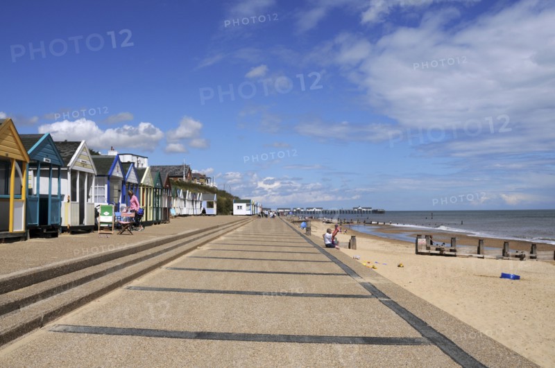 England, Suffolk, Southwold, Beach Huts near the pier with Sea Defences and Holidaymakers. Photo : Bob Battersby