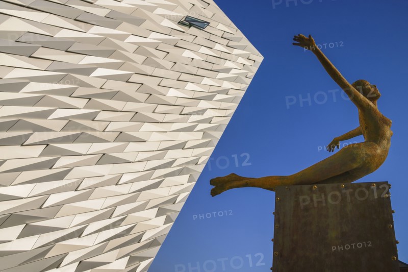 Ireland, North, Belfast, Titanic Quarter, Titanic Belfast Visitor Experience, 'Titanica' sculpture by Rowan Gillespie with a section of the building and blue sky in the background. 
Photo Hugh Rooney