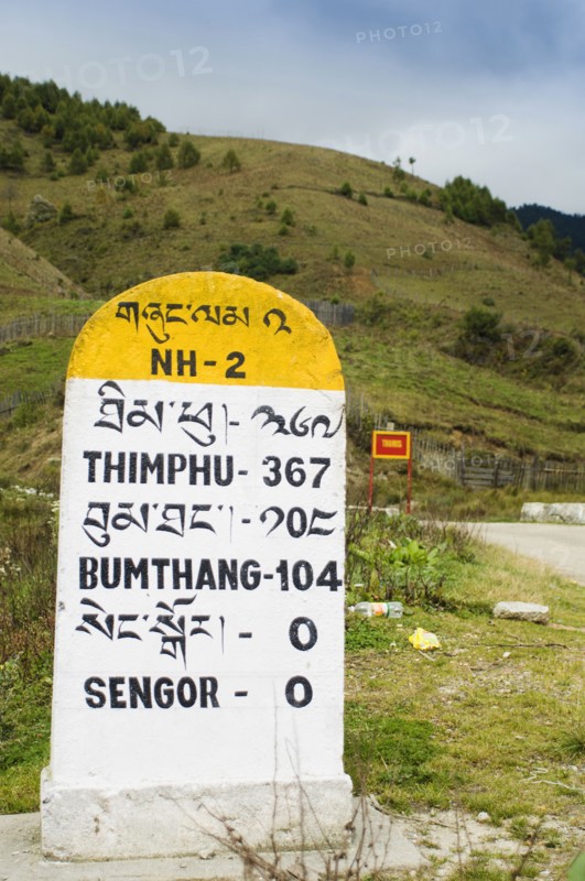 Bhutan, Sengor, Milestones on the side of the main east-west highway showing distances to towns. 
Photo Nic I'Anson