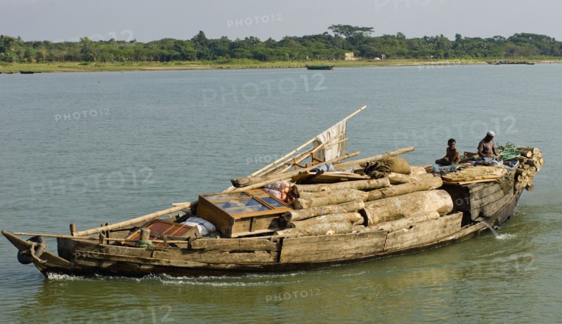 Bangladesh, Industry, Transport, Boat heavily laden with cargo of timber and furniture on river. 
Photo Nic I'Anson