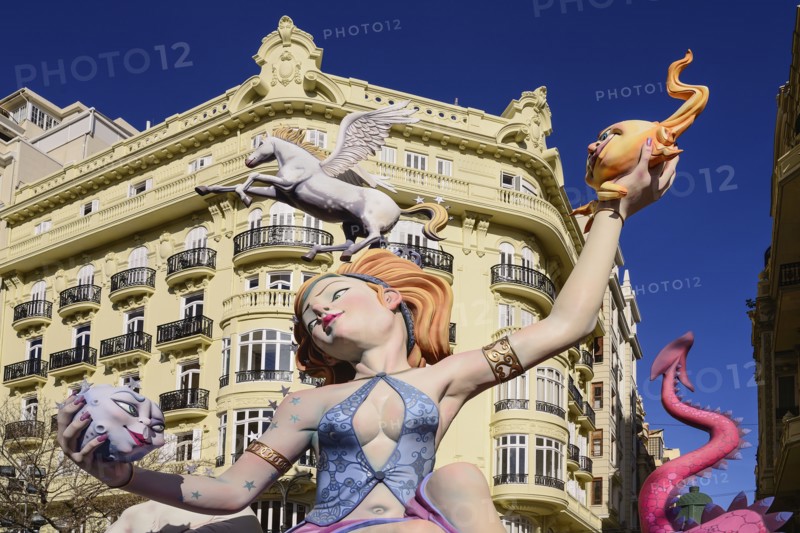 Spain, Valencia Province, Valencia, Female Papier Mache figure with a horse on her head in the street during Las Fallas festival.