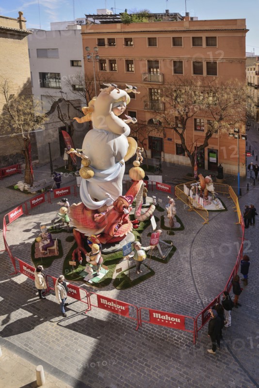 Spain, Valencia Province, Valencia, Papier Mache falla scene with onlookers viewing a giant figure of a lady in the street at Torres de Quart during Las Fallas festival.