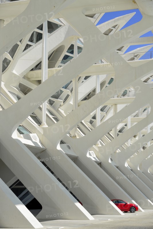 Spain, Valencia Province, Valencia, Spain, Valencia Province, Valencia, La Ciudad de las Artes y las Ciencias, City of Arts and Sciences, Principe Felipe Science Museum, Detail of the building with red Mercedes car protruding from one of the arches. 
Photo Hugh Rooney