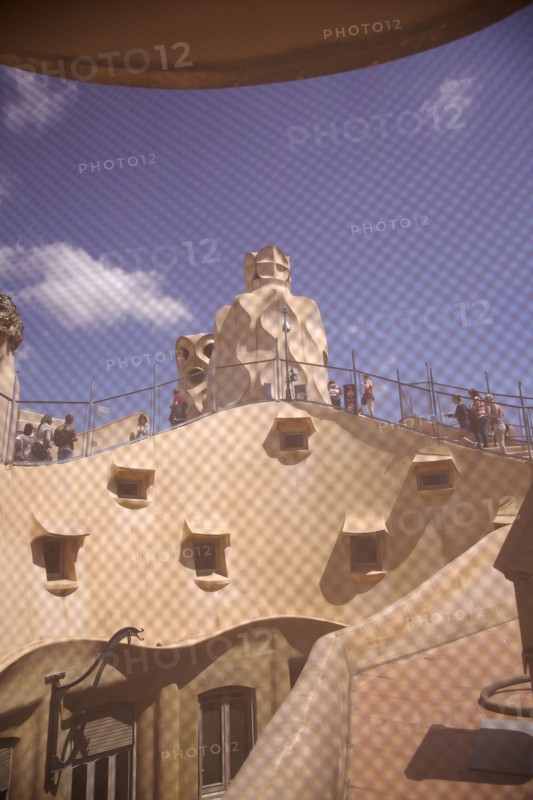 Spain, Catalonia, Barcelona, La Pedrera or Casa Mila on Passeig de Gracia, designed by Antoni Gaudi, view of the roof through mesh covered attic window. 
Photo Stephen Rafferty