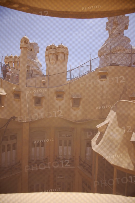 Spain, Catalonia, Barcelona, La Pedrera or Casa Mila on Passeig de Gracia, designed by Antoni Gaudi, view of the roof through mesh covered attic window. 
Photo Stephen Rafferty