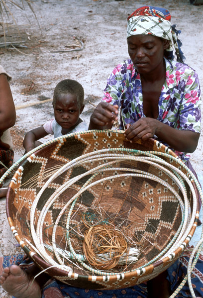 Lady weaving a large basket.