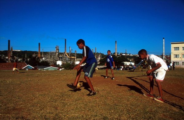 boys playing soccer with factories behind
