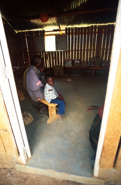 A Samburu child waits with his father or grandfather for medical attention at a mobile clinic set up in a school in the town of Wamba. Samburu men later on in life take young brides in their teens