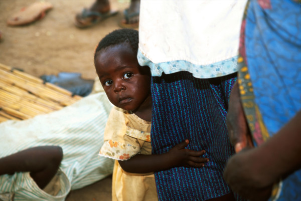 Child peers around mother