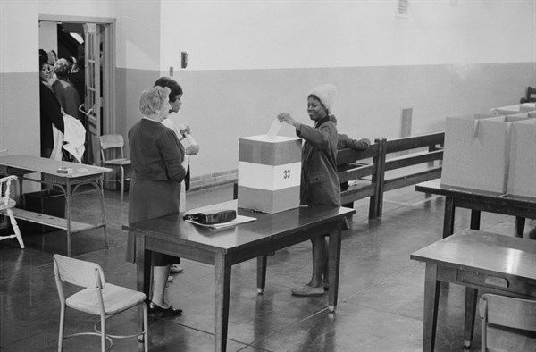 Young African American woman casting her vote in a ballot box