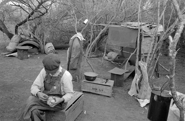 White migrant worker living in camp with two other migrant men
