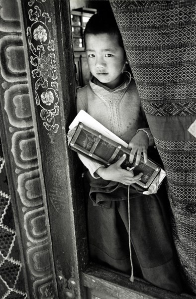 Photograph of a young boy holding a prayer book in Sikkim