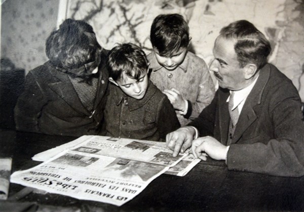 French family read newspaper outlining the liberation of towns in Alsace Lorraine 1944
