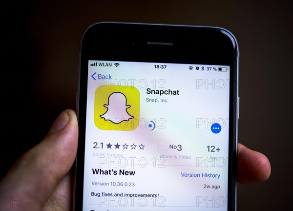 Hand holding iPhone with Snapchat App in the Apple App Store