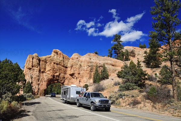 Pickup with caravan drives through a rock gate on Highway 12