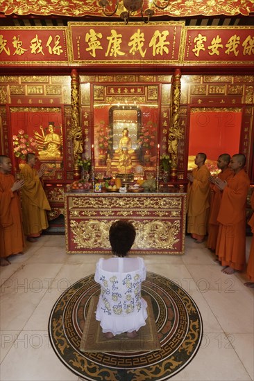 Buddhist Sacrifice Ceremony with praying monks and kneeling woman