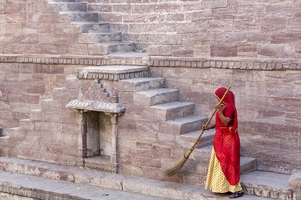 Woman in Sari cleaning the steps at Toorji Ka Jhalara