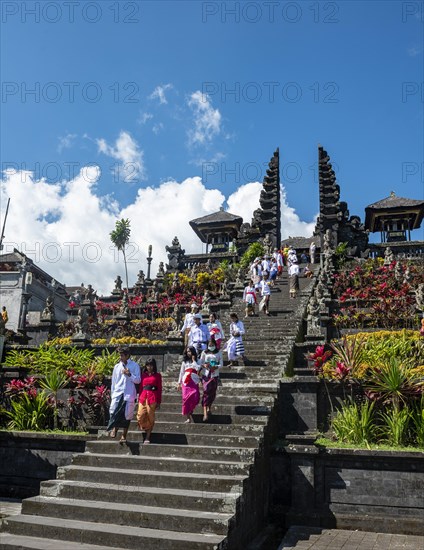 Balinese believers in traditional clothing go down stairs