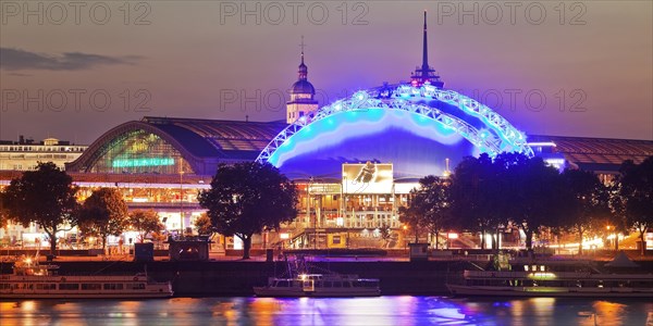 Illuminated Central Station and Musical Dome with Rhine at dusk