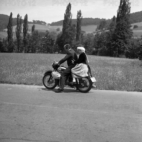 Man and daughter riding a motorbike on a country road