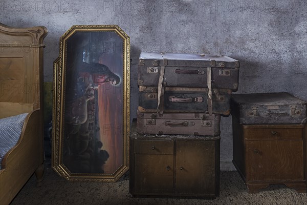 Old suitcases and picture of saint in an attic