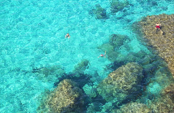 People swimming in the emerald waters of Cala Mitjana