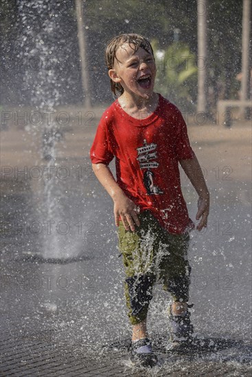 Boy stands in a fountain and gets sprayed