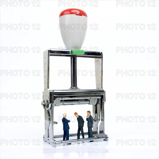 Three figurines representing business men under an ink pad
