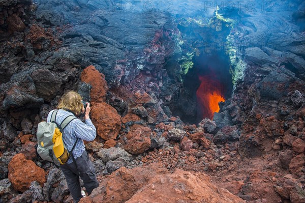 Tourist photographing an active magma stream below the Tolbachik volcano