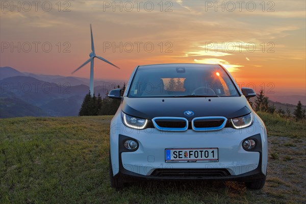 BMW electric car type i3 at the wind farm at sunset
