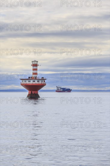 Lighthouse Phare du Haut-Fond Prince in Saint Lawrence River with freighter in the back