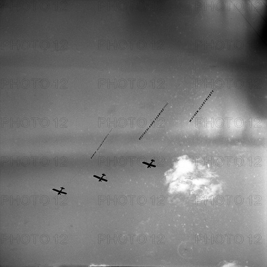 Three airplanes with banner fly synchronously