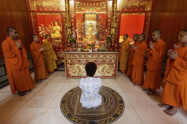 Buddhist Sacrifice Ceremony with praying monks and kneeling woman